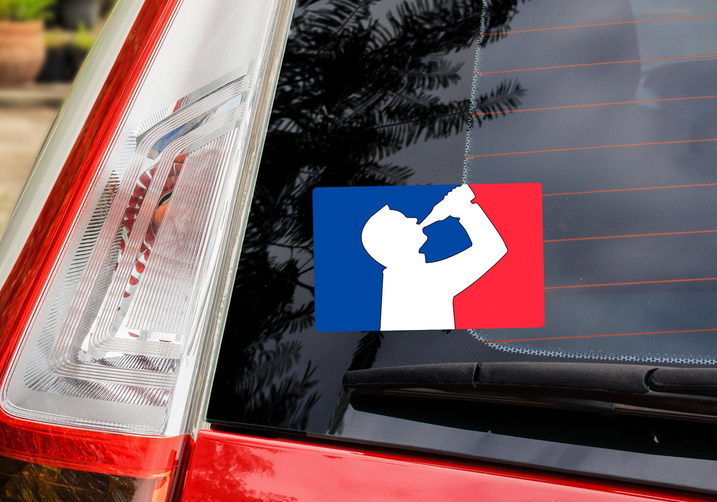 Back window of car with decal sticker. Decal show silhouette of man drinking beer with red and blue background, like professional sports logo