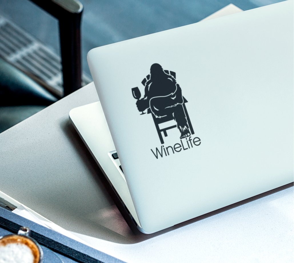 Laptop computer with black decal of Bigfoot relaxing in a chair and enjoying a glass of wine, Wine Life logo below.