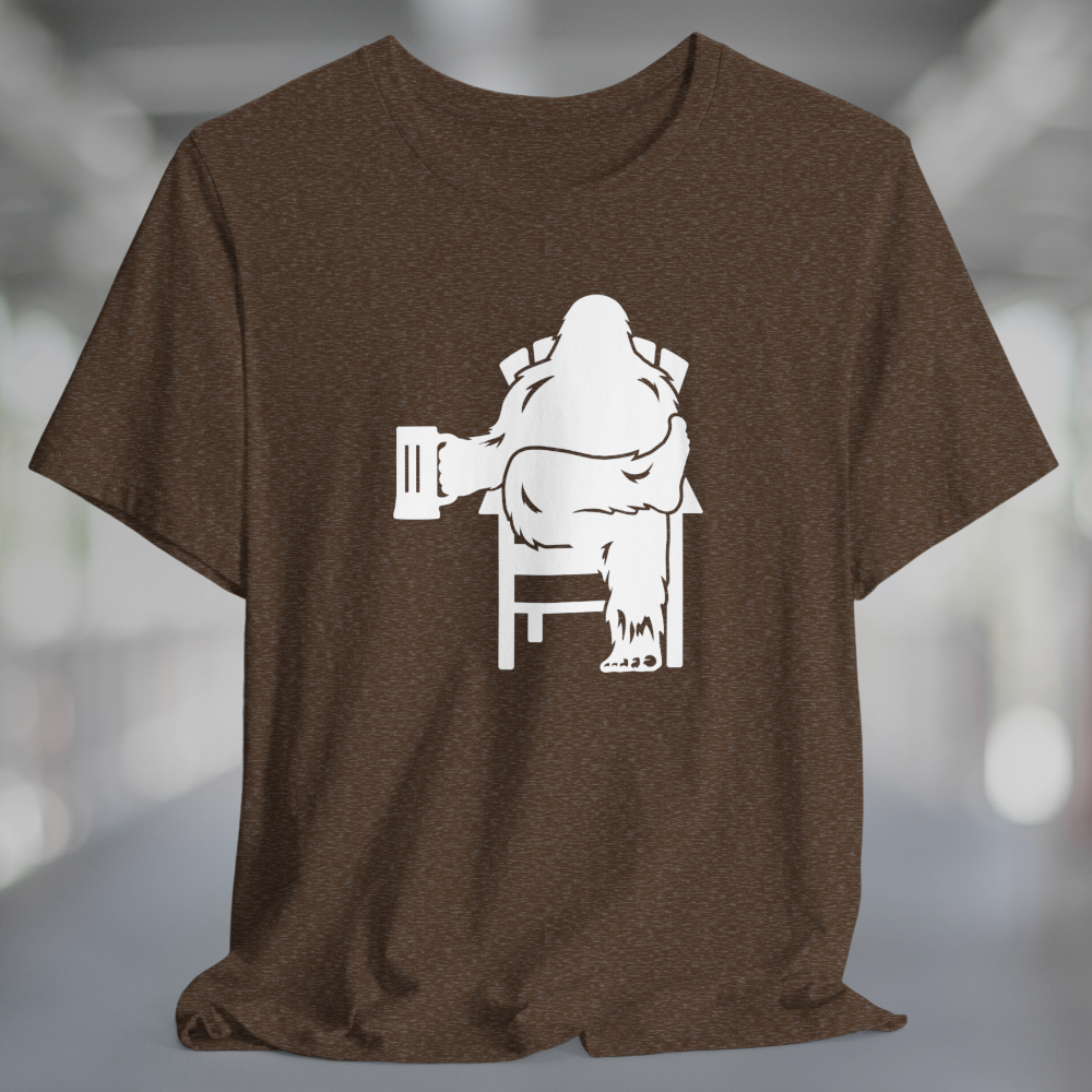 Heather brown t-shirt with white graphic of Bigfoot relaxing in a chair and enjoying a mug of beer.
