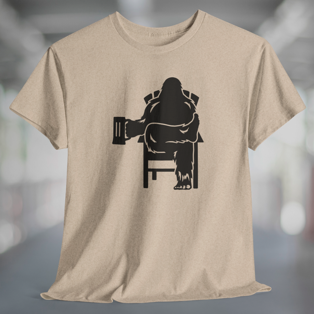 Heather tan t-shirt with black graphic of Bigfoot relaxing in a chair and enjoying a mug of beer.