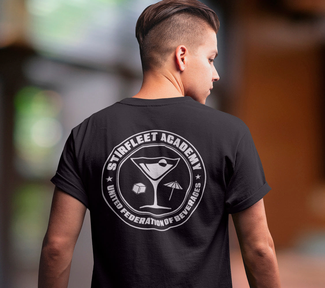 Woman wearing black t-shirt, with white United Federation of Beverages Stirfleet Academy logo, martini glass ice cube umbrella graphic on back of shirt.