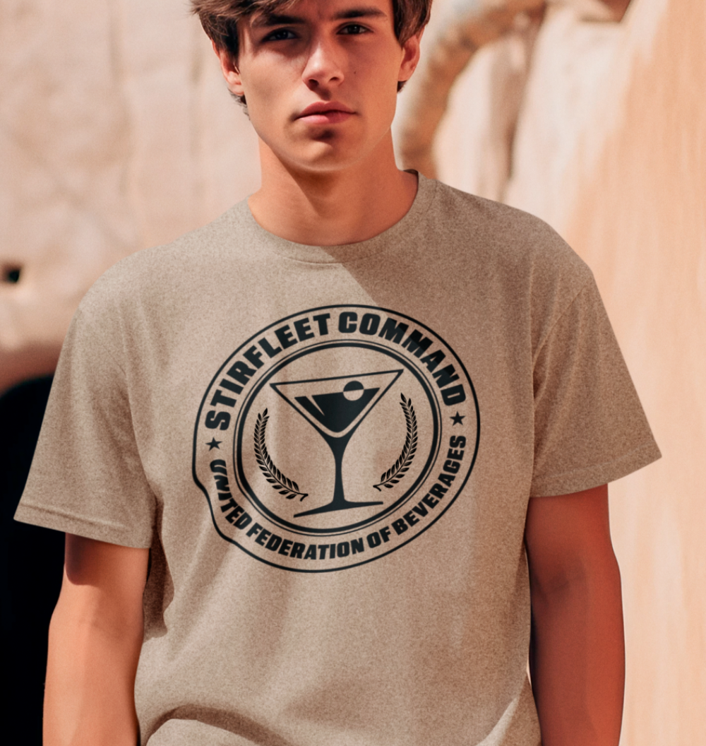 Man wearing heather tan t-shirt, with black United Federation of Beverages Stirfleet Command logo, martini glass graphic on front of shirt.