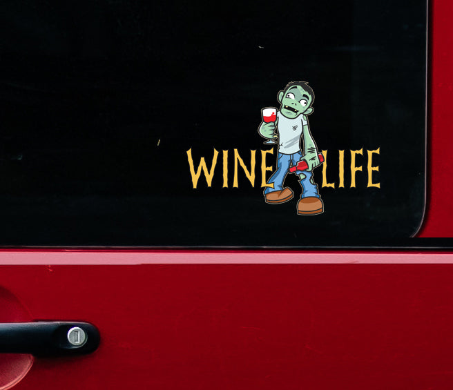 Side window of red truck with sticker decal of cartoon zombie holding wine glass and bottle of wine, with wine life logo in spooky font.