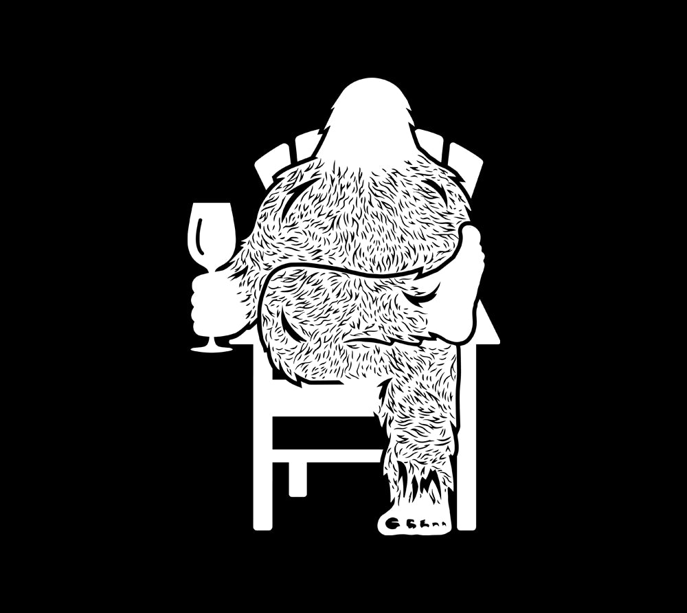 Bigfoot Wine T-Shirt featuring a humorous Sasquatch character holding a glass of wine while relaxing on a chair.