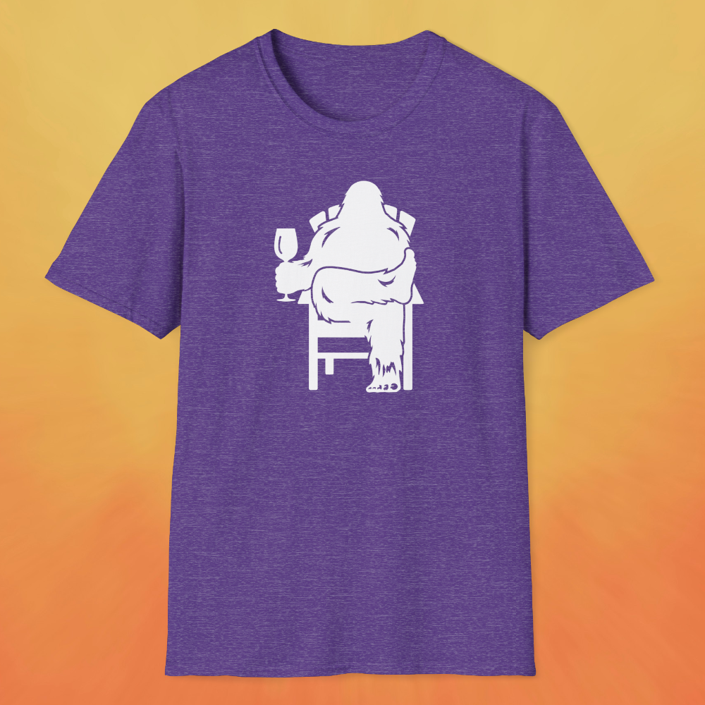 Heather purple t-shirt with white print of Bigfoot relaxing in a chair and enjoying a glass of wine.