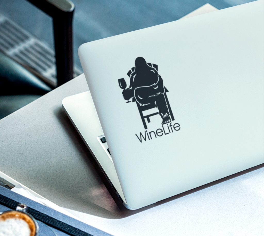 Laptop computer with black decal of Bigfoot relaxing in a chair and enjoying a glass of wine, Wine Life logo below.