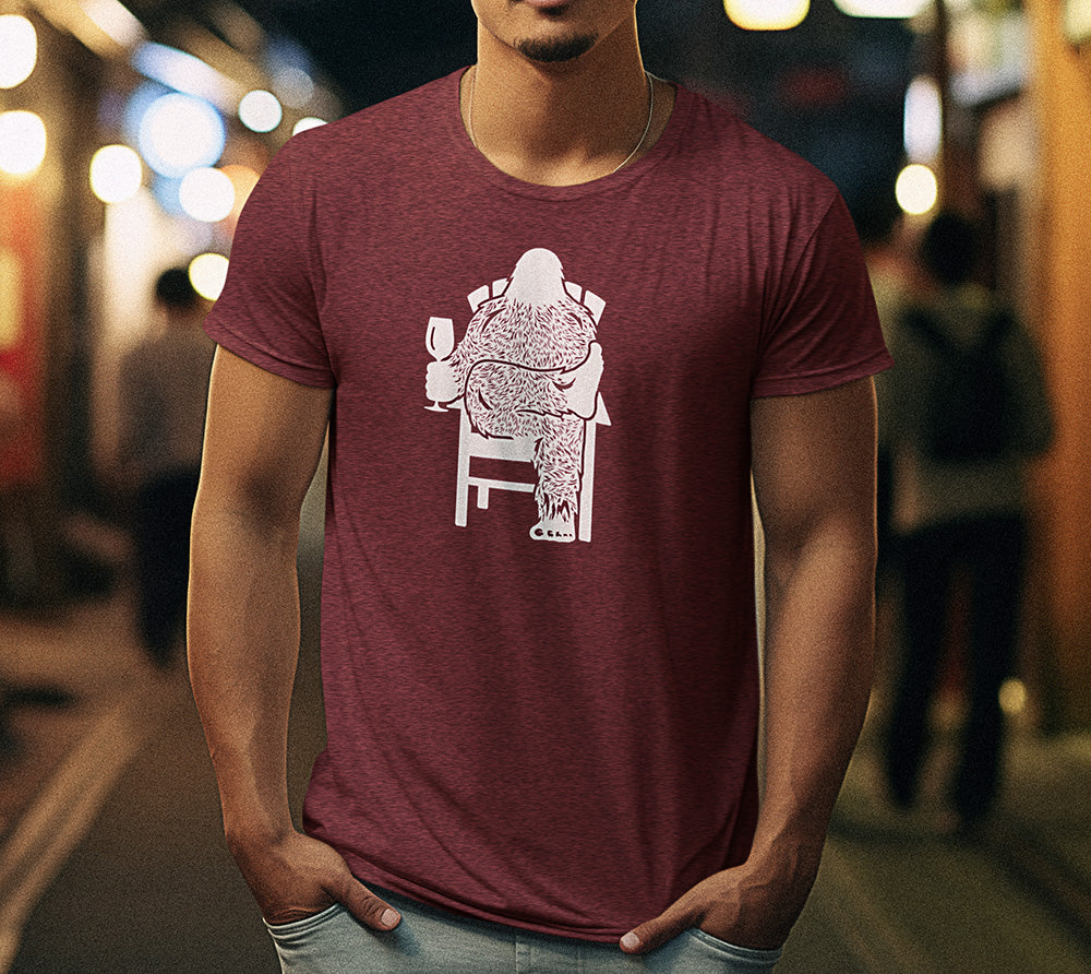 Bigfoot Wine T-Shirt featuring a graphic of Sasquatch relaxing in a chair with a glass of wine.