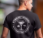 Woman wearing black t-shirt, with white United Federation of Beverages Stirfleet Academy logo, martini glass ice cube umbrella graphic on back of shirt.