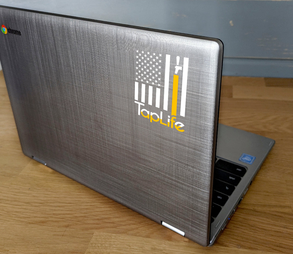 Laptop computer with decal of American flag with one yellow stripe pouring from a beer tap, Tap Life logo below