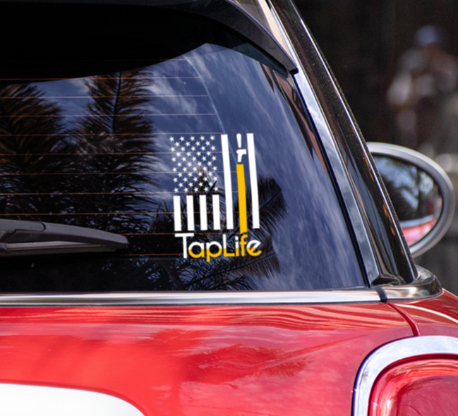 car rear window with decal sticker of American flag with one yellow stripe pouring from a beer tap, Tap Life logo below