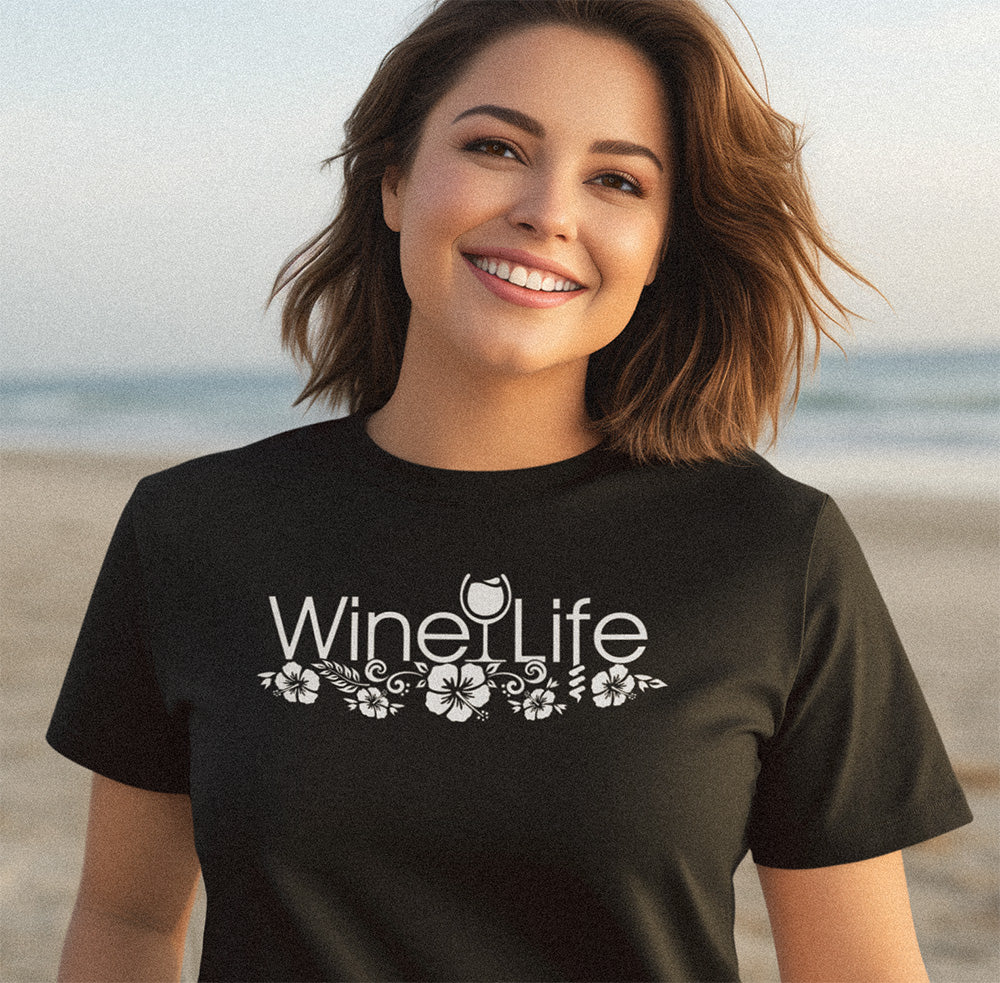 Hawaiian 'Wine Life' design with hibiscus in white on a black t-shirt, with a woman on a beach