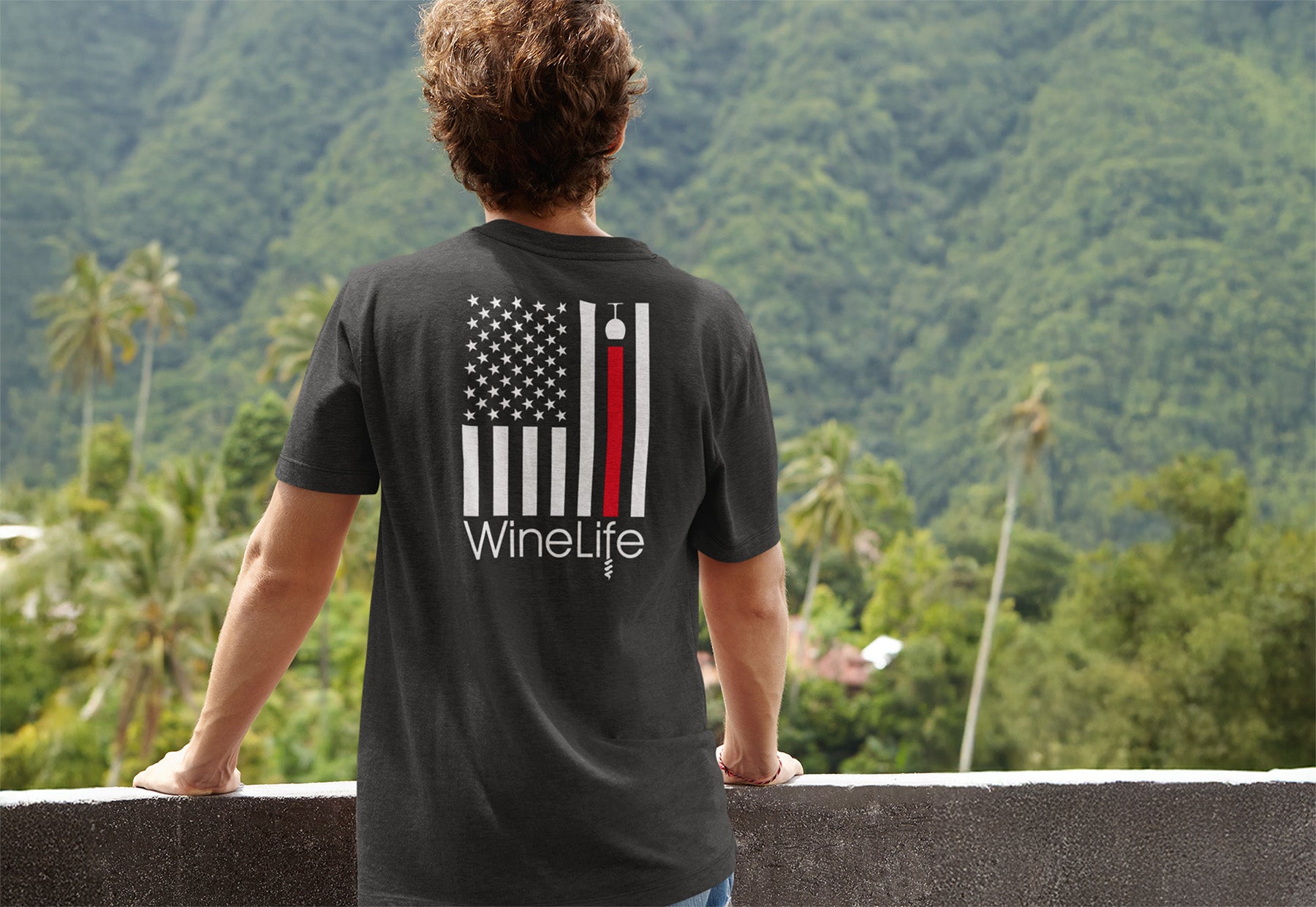 Person wearing a black t-shirt with a U.S. flag design and 'WineLife' text, standing against a scenic mountain backdrop.