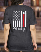 Woman wearing Heather charcoal gray t-shirt with print of American flag with one red stripe pouring from a wine glass and Wine Life logo below on back