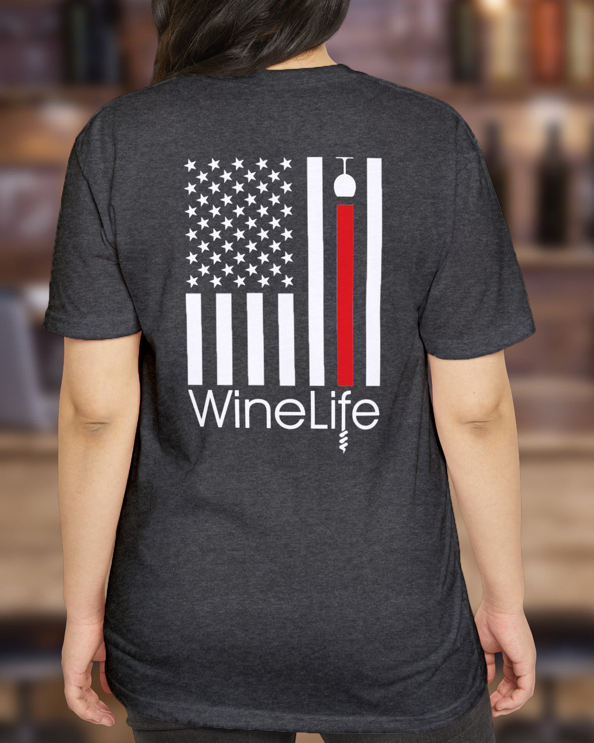 Woman wearing Heather charcoal gray t-shirt with print of American flag with one red stripe pouring from a wine glass and Wine Life logo below on back