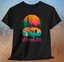 Black t-shirt with colorful camper, background of trees, mountains, sun and birds, above red wine life logo