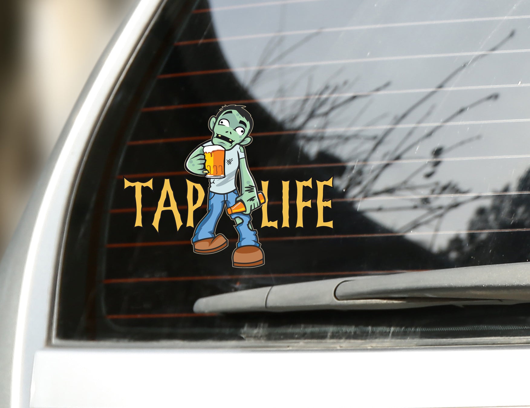 Rear car window with sticker decal of cartoon zombie holding beer mug and bottle of beer, with tap life logo in spooky font.